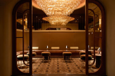 Opulent amber-lit cocktail bar with tiered glass chandelier and leather banquettes at The Newman private event spaces Fitzrovia
